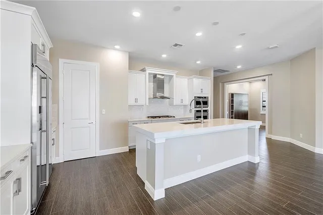 a large kitchen with stainless steel appliances granite countertop a large center island a stove a refrigerator and cabinets