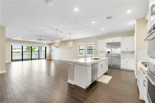 a large kitchen with stainless steel appliances granite countertop a large center island a sink a stove and a refrigerator