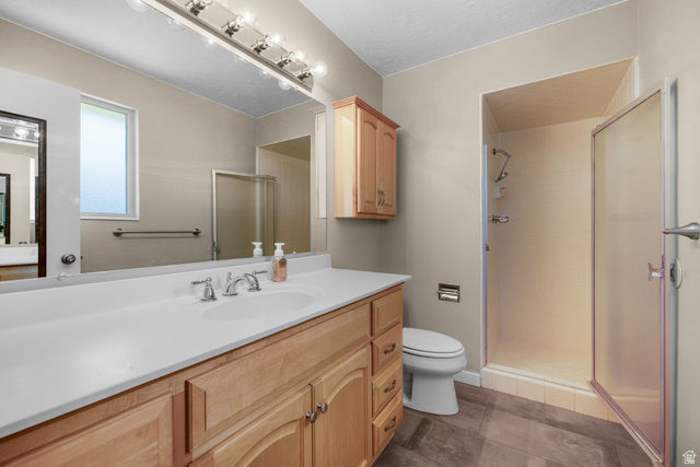 2088 Falcon Way Sandy, UT 84093 - Photo 26 of 46 Bathroom featuring a single-basin vanity with wood cabinetry and a light-toned countertop, a frameless mirror, and a shower enclosure with a frosted glass door