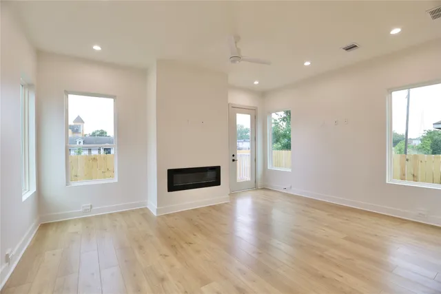 a view of an empty room with a window and wooden floor
