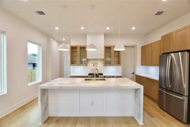a kitchen with kitchen island granite countertop a refrigerator and a sink