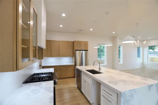 a kitchen with stainless steel appliances granite countertop a sink a stove and a refrigerator