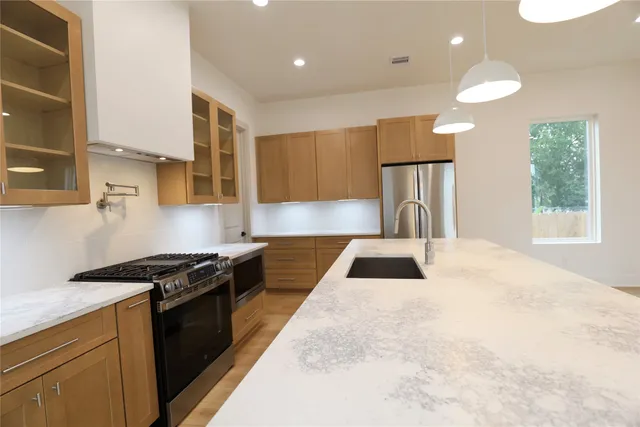 a kitchen with granite countertop a stove a sink and a refrigerator