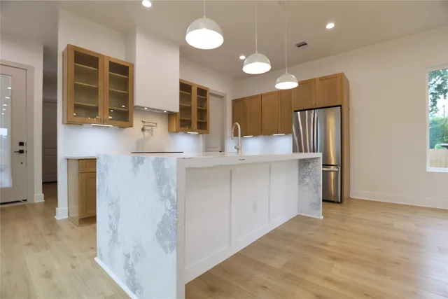 a kitchen with stainless steel appliances kitchen island granite countertop a refrigerator and a sink
