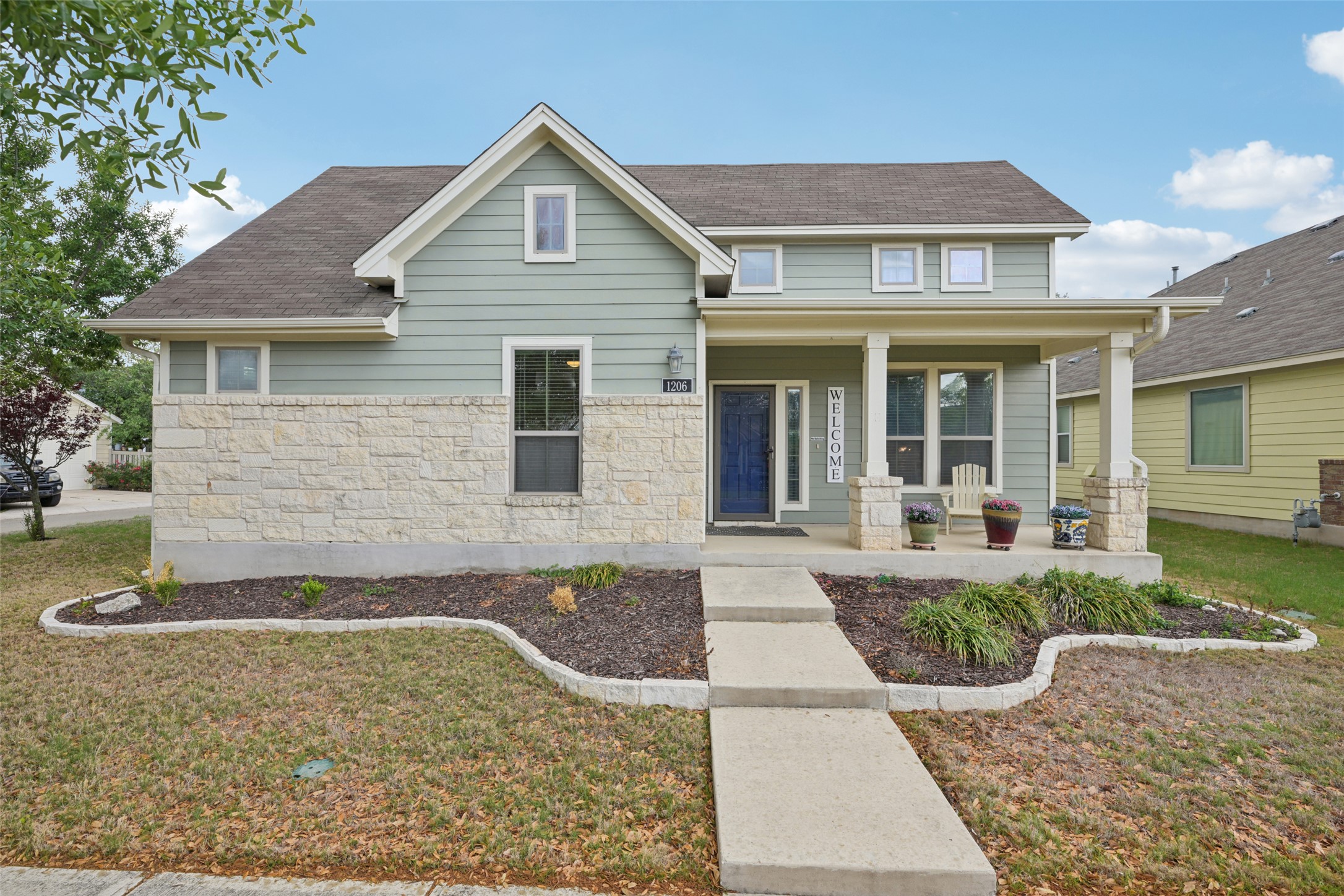 View of front of property with a porch, stone siding, and a front​​‌​​​​‌​​‌‌​‌‌​​‌​​​​‌​​​‌‌​‌‌‌ yard