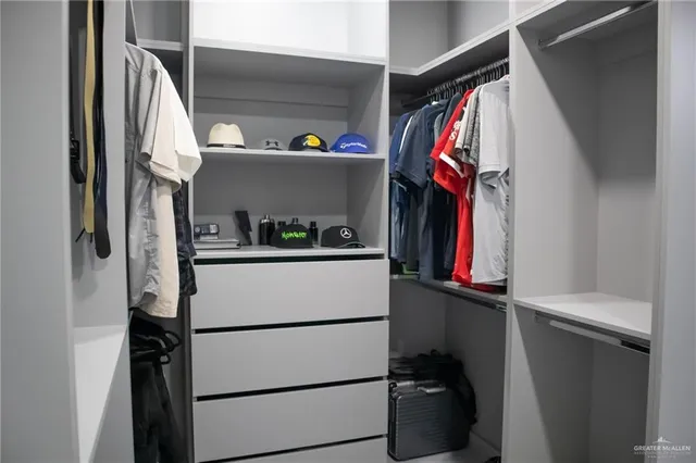 a view of walk in closet with clothes and shoes