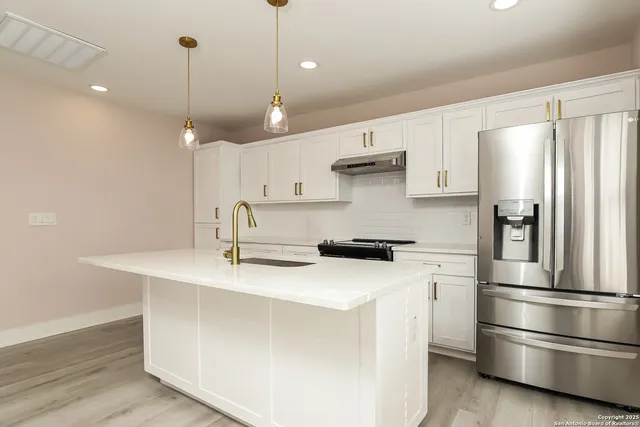 a kitchen with stainless steel appliances a refrigerator sink and wooden floor