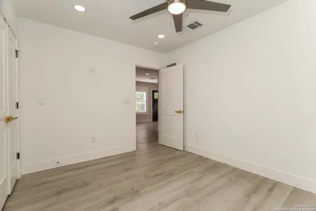 an empty room with wooden floor and ceiling fan