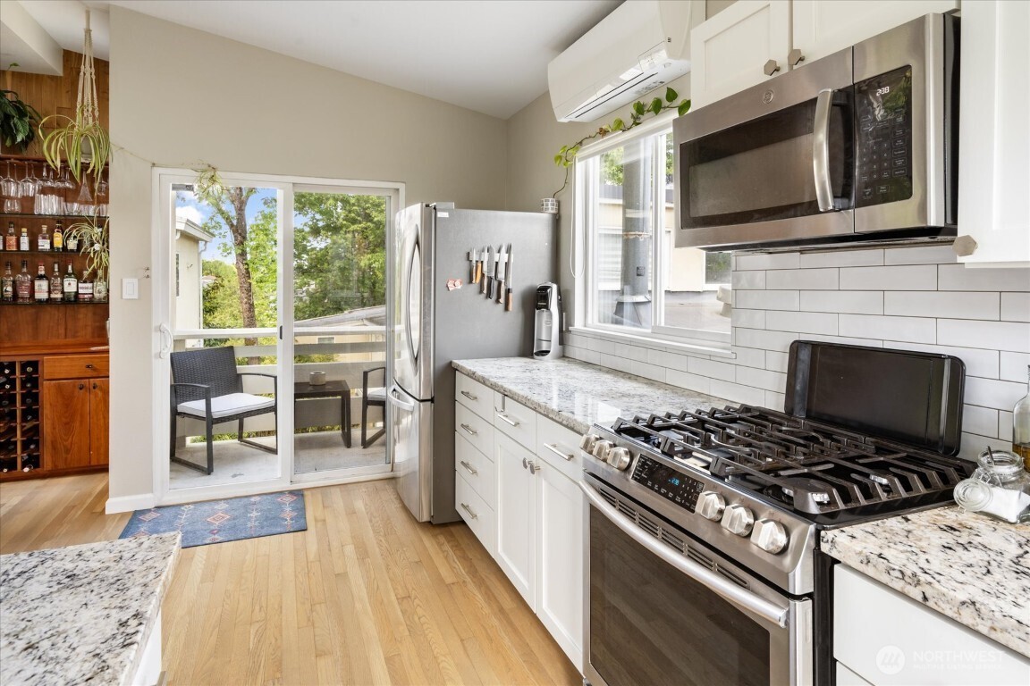 1724 26th Avenue Seattle, WA 98122 - Photo 13 of 28 a kitchen with stainless steel appliances granite countertop a stove top oven a sink dishwasher a dining table and chairs with wooden floor