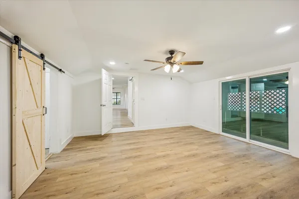 a view of empty room with wooden floor and fan