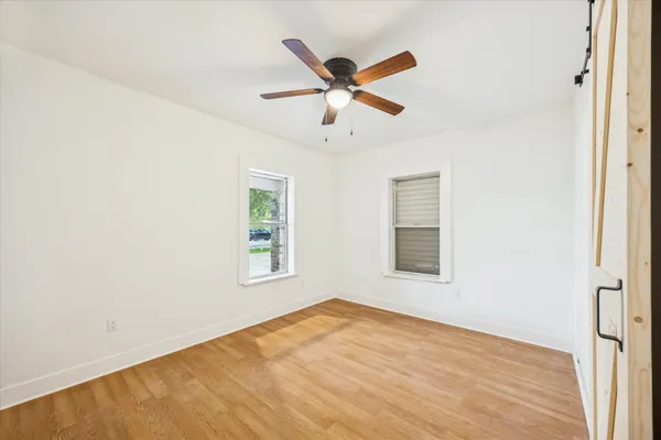 a view of an empty room with wooden floor and a window