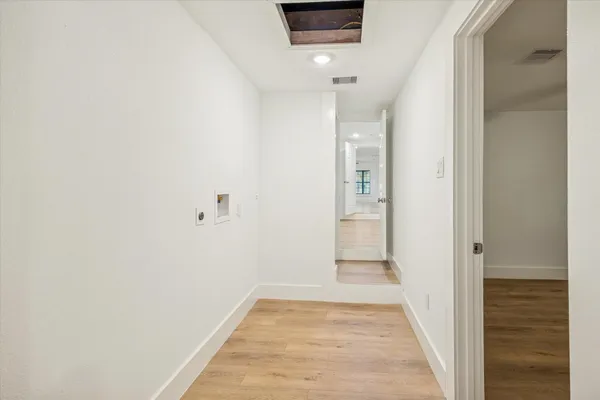 a view of a hallway with wooden floor and a bathroom