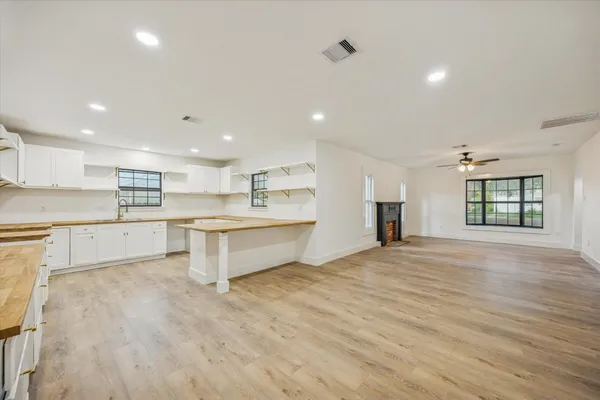 a large white kitchen with kitchen island a sink dishwasher a stove and a refrigerator with wooden floor