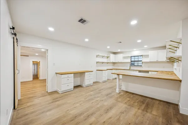 a large white kitchen with wooden floor and a sink