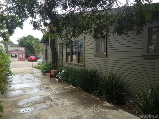 a pathway of a house with potted plants and large trees