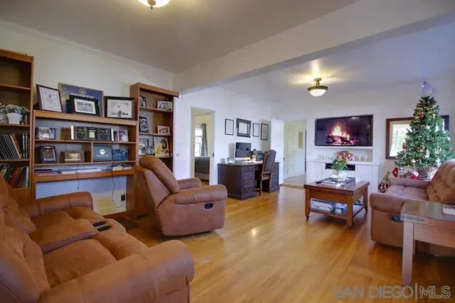 a living room with furniture and a bookshelf with wooden floor