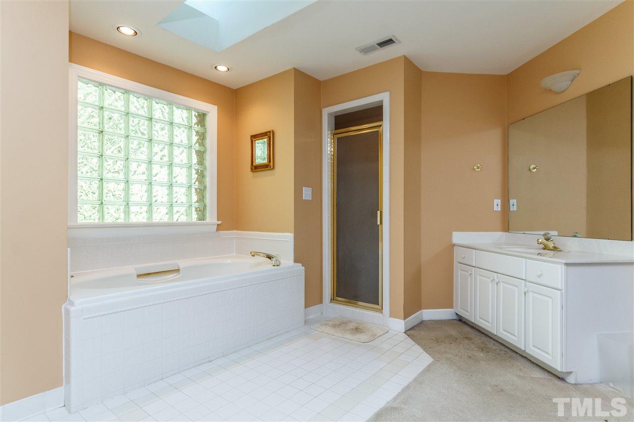 644 Pendleton Lake Road Raleigh, NC 27614 - Photo 23 of 25 a spacious bathroom with a double vanity sink a large mirror and a bathtub