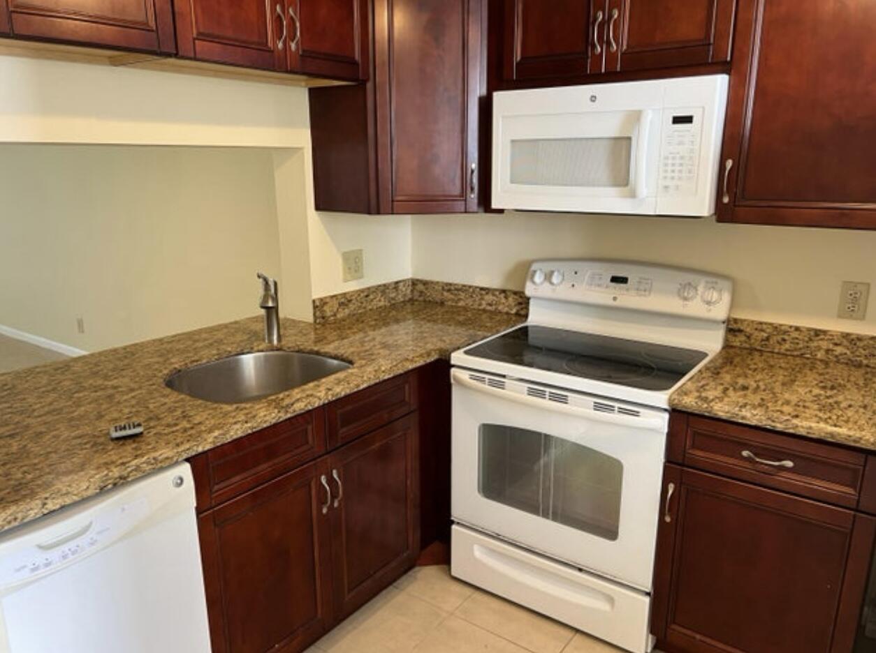 1256 South Military Trail, Unit 911 Deerfield Beach, FL 33442 - Photo 14 of 17 a kitchen with granite countertop a sink a stove and cabinets