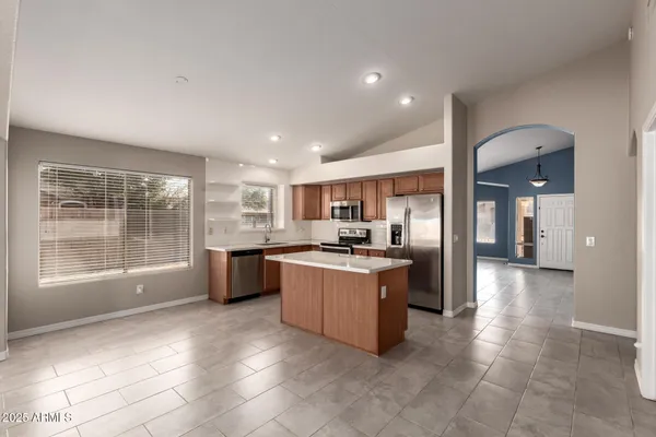 a large kitchen with kitchen island a large window a sink and stainless steel appliances