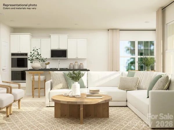 a living room with a couch a flat screen tv and kitchen view