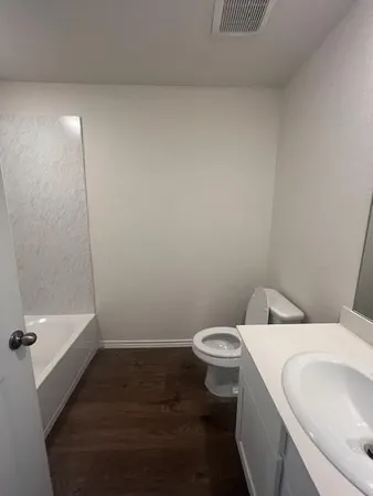a white toilet sitting next to a bath tub