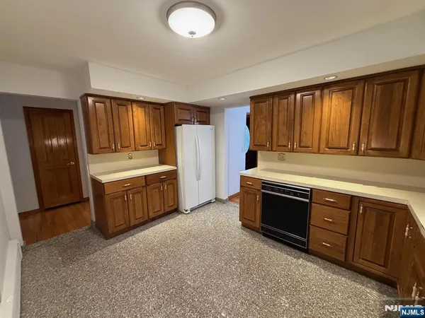 a kitchen with stainless steel appliances granite countertop a stove a sink dishwasher a refrigerator and wooden cabinets