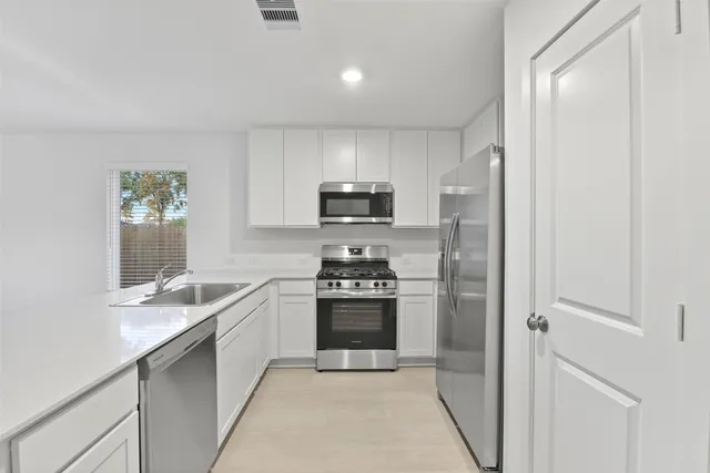 a kitchen with granite countertop white cabinets and stainless steel appliances