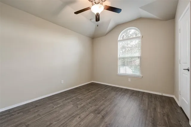 an empty room with wooden floor chandelier fan and windows