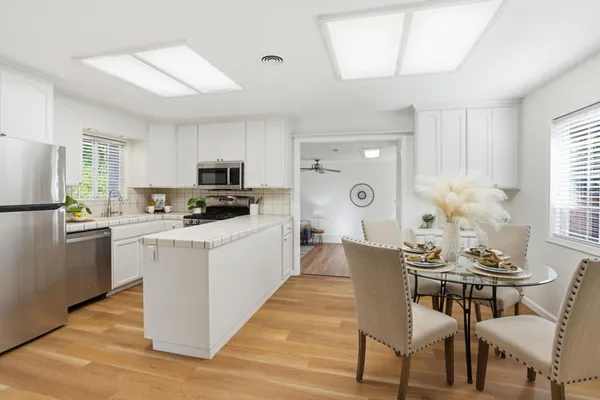 a kitchen with a dining table chairs and refrigerator