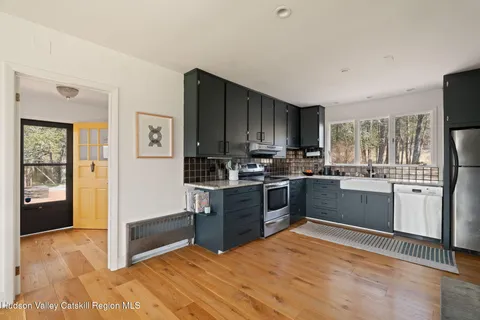 a kitchen with granite countertop a stove a sink dishwasher a refrigerator and a oven with wooden floor