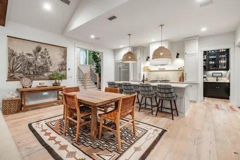 a open kitchen with stainless steel appliances granite countertop a dining table chairs sink and stove top oven