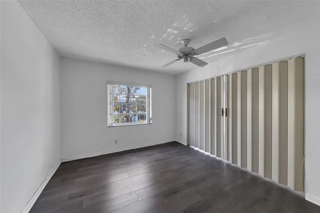 an empty room with wooden floor and ceiling fan