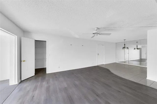 an empty room with wooden floor and a ceiling fan