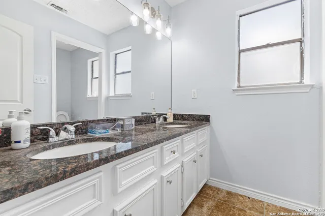 a bathroom with a granite countertop sink and a mirror