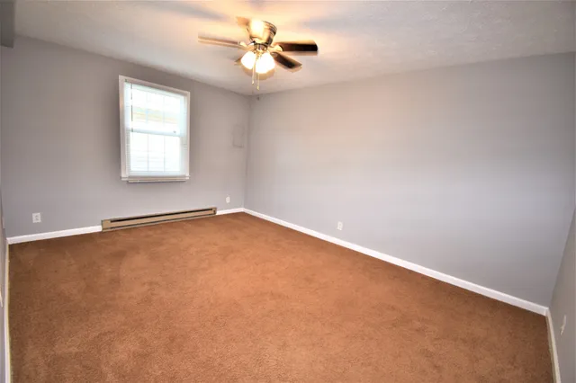 an empty room with a window and a fan