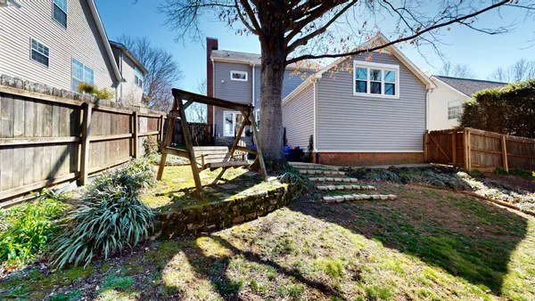 a view of backyard with wooden fence and large trees