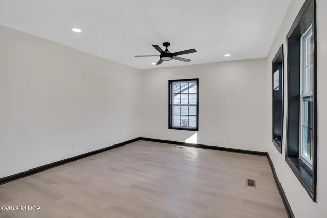 an empty room with windows and a ceiling fan