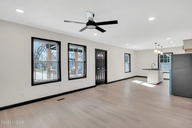 a view of an empty room with a window and kitchen view
