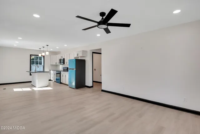 a view of an empty room with a ceiling fan and kitchen floor