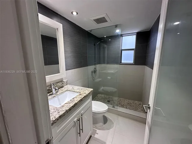 a bathroom with a granite countertop sink a toilet and a mirror