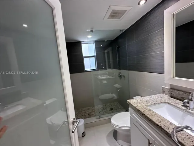 a bathroom with a granite countertop toilet a sink and a mirror