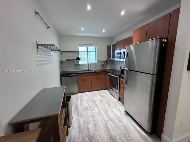a kitchen with kitchen island a counter top space wooden floor and stainless steel appliances