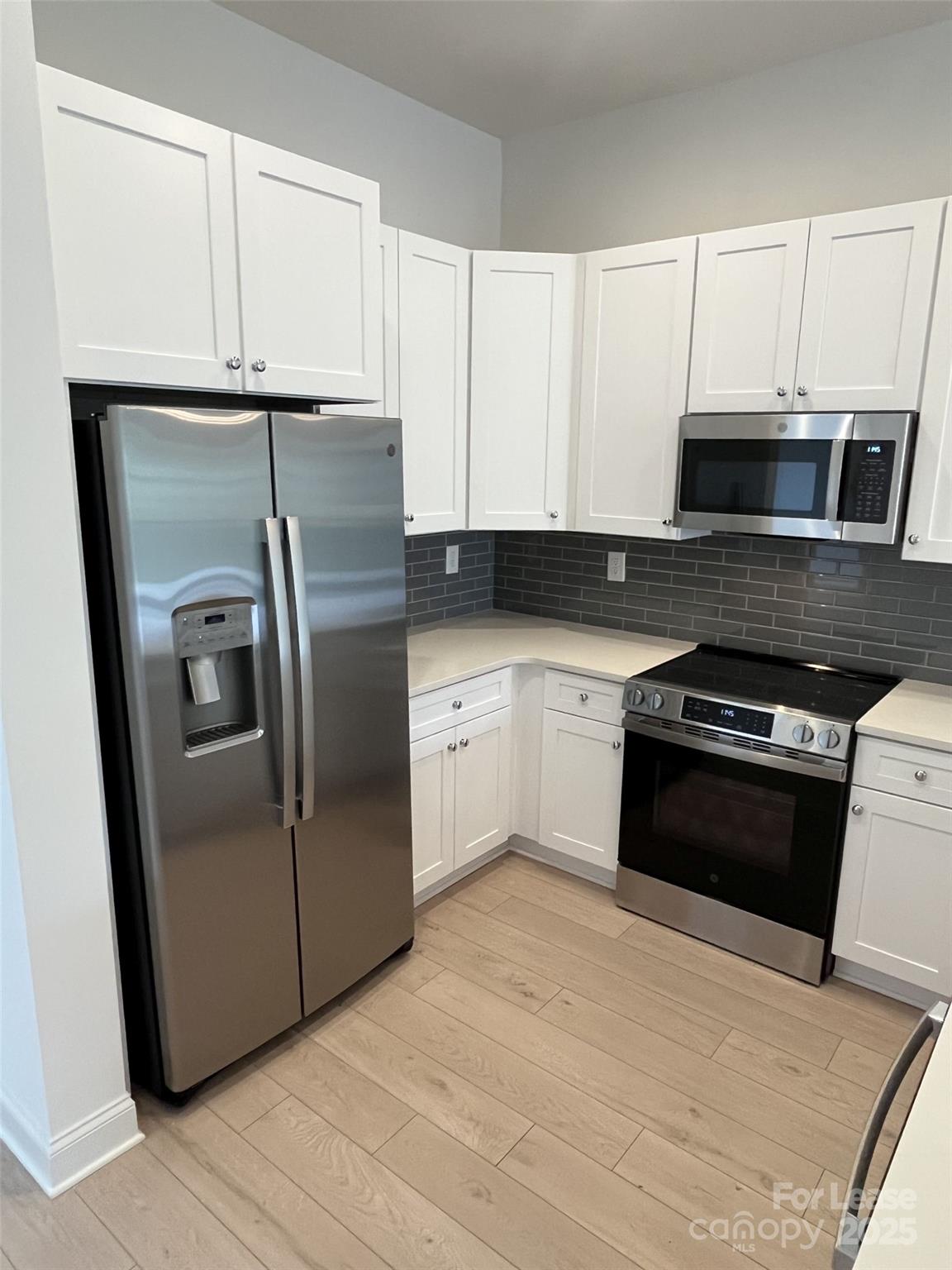 19546 Greentree Way, Unit 203 Cornelius, NC 28031 - Photo 11 of 32 a kitchen with granite countertop a refrigerator and a stove top oven