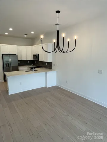 an empty room with wooden floor and kitchen view