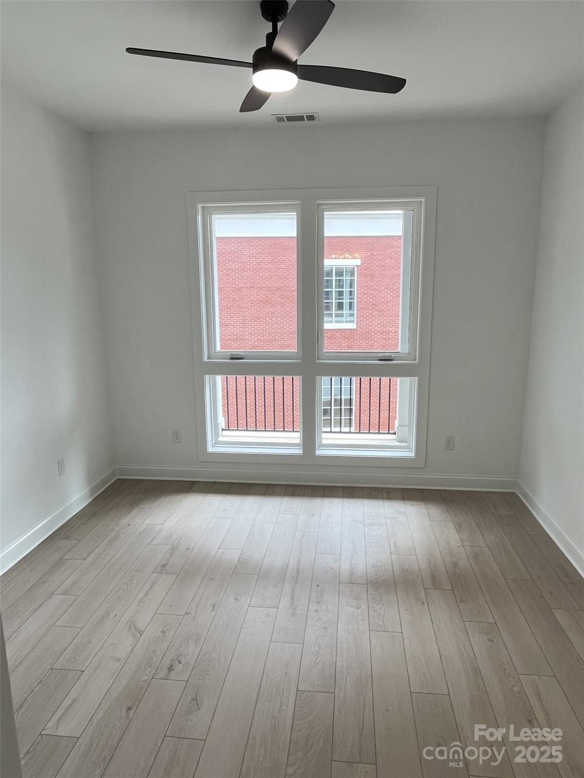 19546 Greentree Way, Unit 203 Cornelius, NC 28031 - Photo 26 of 32 an empty room with wooden floor fan and windows