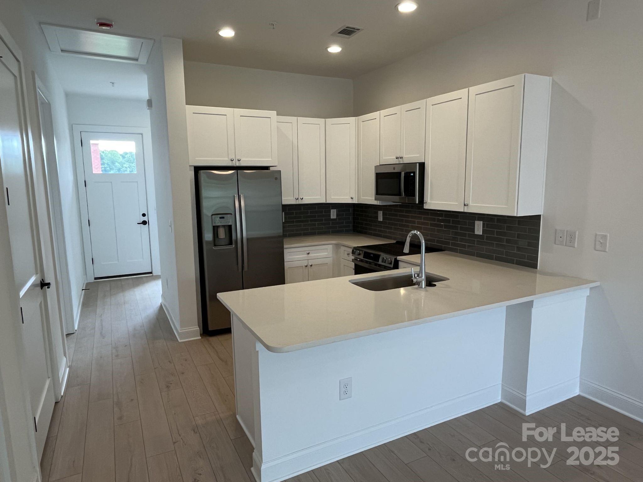 19546 Greentree Way, Unit 203 Cornelius, NC 28031 - Photo 10 of 32 a kitchen with a sink a refrigerator and cabinets