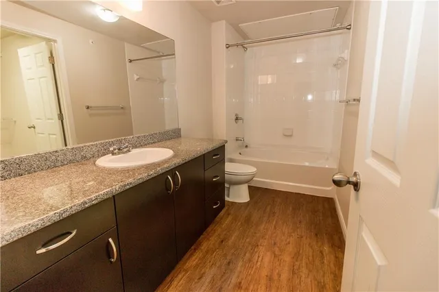 a bathroom with a granite countertop sink toilet a large mirror a shower and bathtub