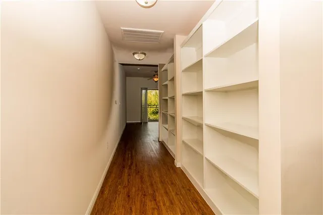 a view of a hallway with wooden floor and a bathroom