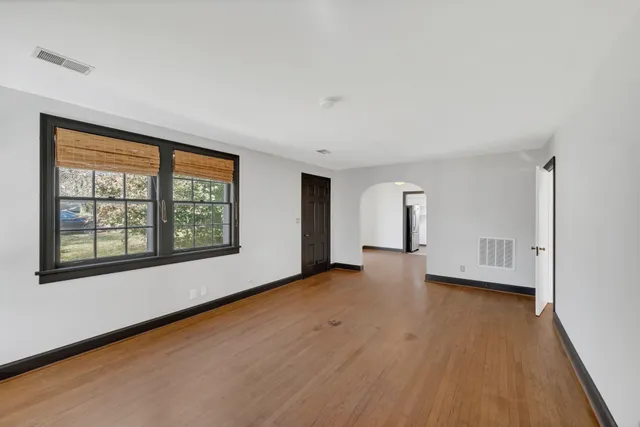 a view of an empty room with a window and wooden floor