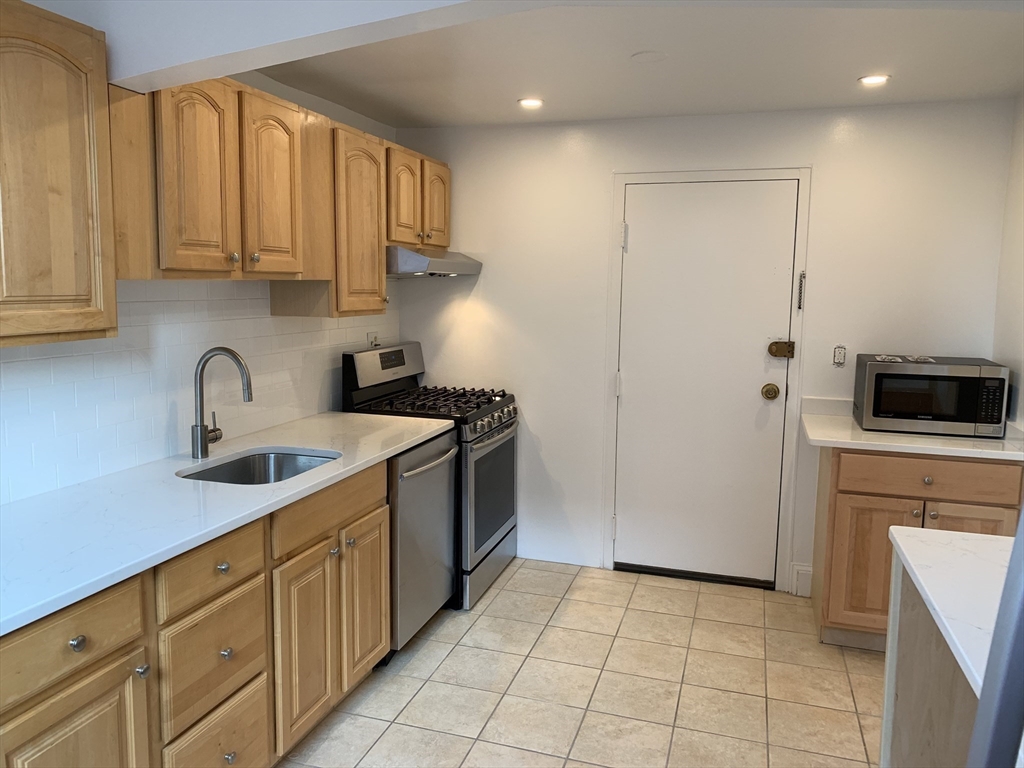 1064 Beacon Street, Unit 9 Brookline, MA 02446 - Photo 5 of 19 a kitchen with stainless steel appliances granite countertop a refrigerator sink and cabinets